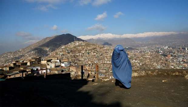 An Afghan woman walks on a hilltop overlooking Kabul
