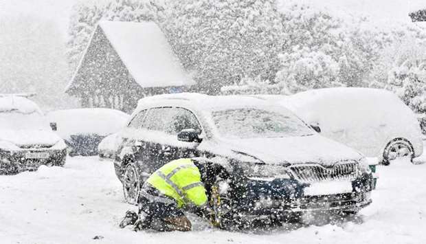 A man fits snow chains to his car in the village of Brenchley in southeast England