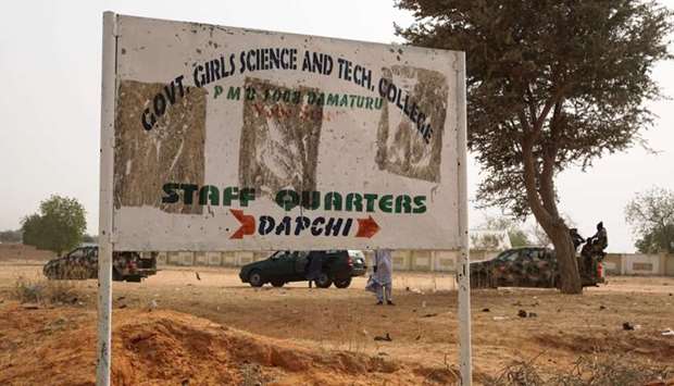 Soldiers (R) drive past a signpost leading to the Government Girls Science and Technical College staff quarters in Dapchi, Nigeria, last Thursday.