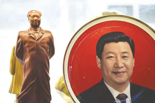 A decorative plate featuring an image of Chinese President Xi Jinping is seen beside a statue of late communist leader Mao Zedong at a souvenir store next to Tiananmen Square in Beijing.