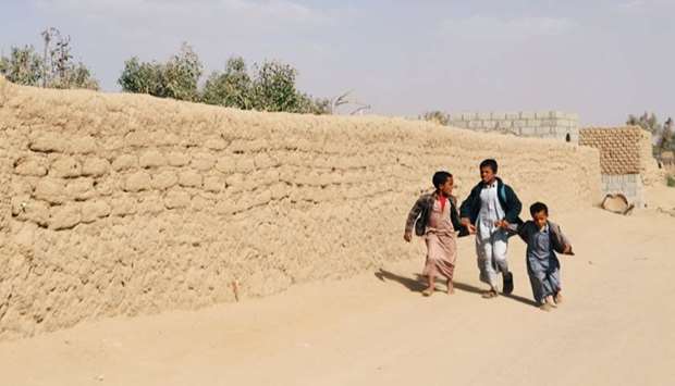 Boys walk as they flee an area where air strikes hit a house in Saada, Yemen