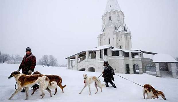 People walk their greyhound Barzoi dogs near a cathedral in Kolomenskoye museum-reserve during a snowfall in Moscow on Sunday.