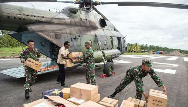 File photo shows Indonesian soldiers along with a local resident unloading food and medical aid in Ewer, Asmat District, in the remote region of Papua, Indonesia.