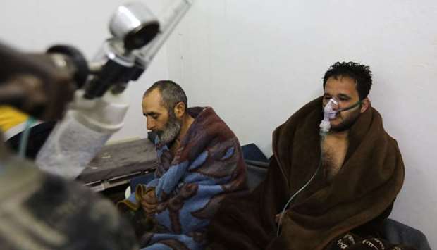 Syrians reportedly suffering from breathing difficulties following Syrian regime air strikes on the northwestern town of Saraqeb rest around a stove at a field hospital in a village on the outskirts of Saraqeb, due to the lack of hospitals in the town, yesterday.