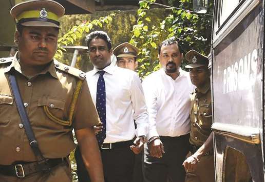 Bond dealer Arjun Aloysius, second left, is escorted to a prison bus in Colombo yesterday after he was remanded in custody until February 16 after being accused of causing millions of dollars in losses to the state.