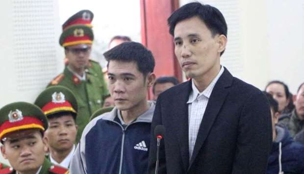 Vietnamese prominent activists Hoang Duc Binh and Nguyen Nam Phong stand at a court in Nghe An province