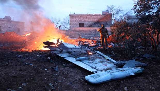 A picture taken on February 3, 2018, shows a Rebel fighter taking a picture of a downed Sukhoi-25 fighter jet in Syria's northwest province of Idlib.