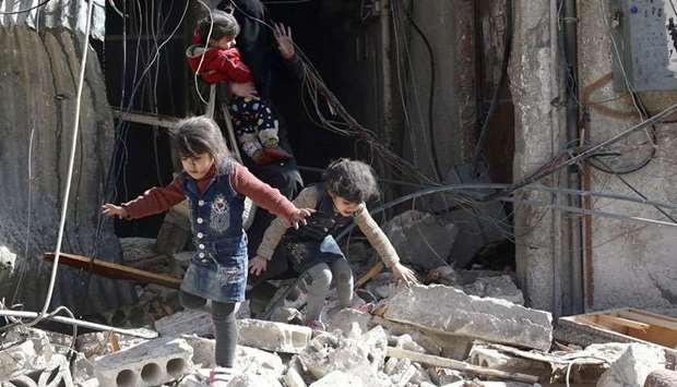 Children walk on rubble of damaged buildings after an airstrike in the besieged town of Douma in eastern Ghouta in Damascus, Syria