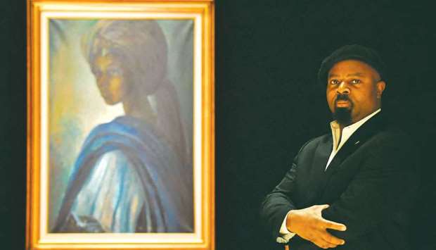 Nigerian author Ben Okri poses with a work of art by Nigerian painter and sculptor Ben Enwonwu entitled u2018Tutuu2019 at the Bonhams auction house in London.
