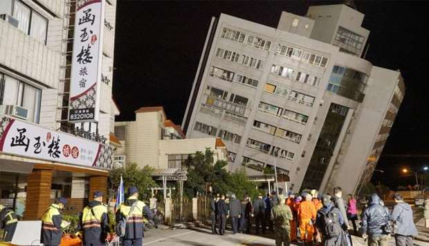 Rescue workers block off the area to search for survivors outside a building which tilted to one side after its foundation collapsed in Hualien after a strong 6.4-magnitude quake rocked eastern Taiwan
