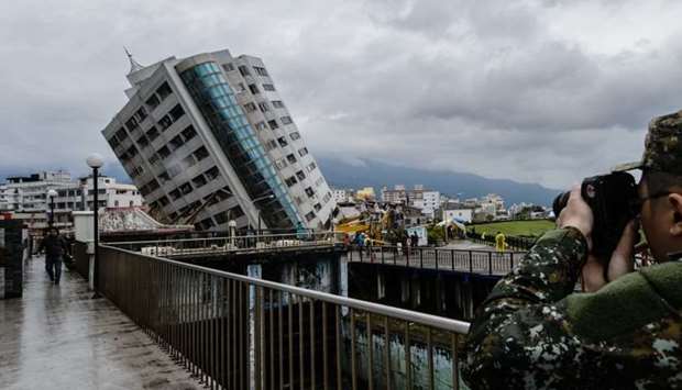 A rescue worker takes a photo of the Yun Tsui building, which is leaning at a precarious angle, in the Taiwanese city of Hualien