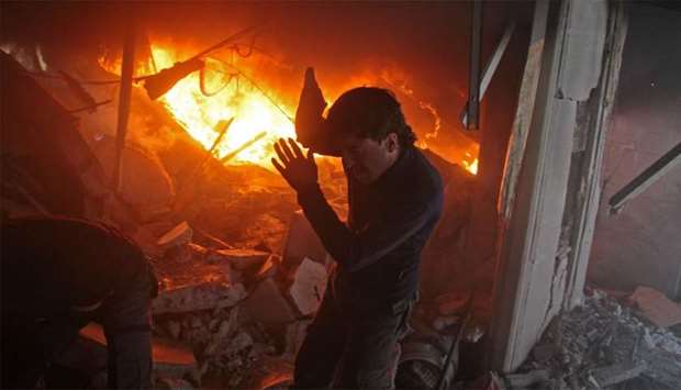 A Syrian man searches for people in a fire following regime air strikes on the rebel-held besieged town of Douma