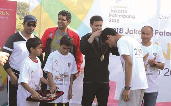 Qatar Olympic Committee secretary-general Jassim al-Buenain presents medals to schoolchildren who participated in the Fun Run at Aspire Park yesterday.