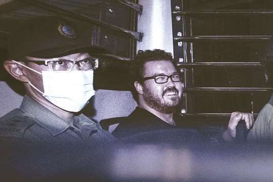 British banker Rurik Jutting, charged with the grisly murders of two Indonesian women, smiling as he sits in a prison van leaving the Eastern Court in Hong Kong, in this file picture.