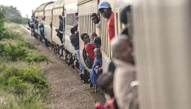 Passengers hang on the sides of commuter train in Bulawayo.