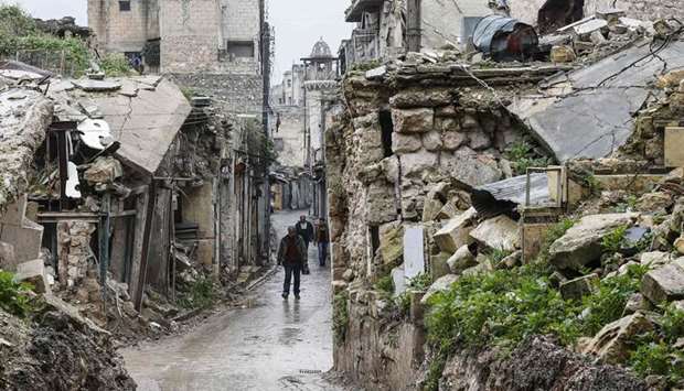 Syrian people walk amid destruction in the Bab al-Qinnasrin area in Aleppou2019s Old City, yesterday.
