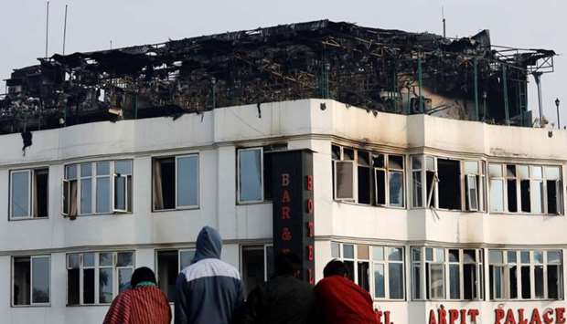 Onlookers stand on the rooftop of a building as they look at a hotel where a fire broke out in New Delhi, India.