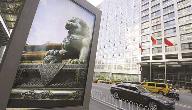 An advertising board (left) showing a Chinese stone lion is pictured near an entrance to the  headquarters (right) of China Securities Regulatory Commission in Beijing (file). Chinau2019s securities regulator has started to remove many of the curbs designed to keep out speculators, signalling an end to the highly-restrictive era that started when a boom in the countryu2019s stocks turned to bust in 2015.