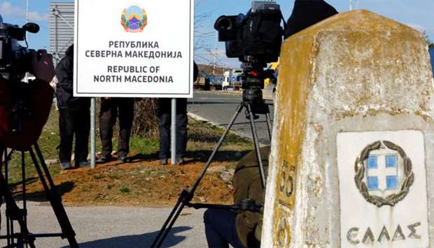 Workers set up a sign with Macedonia's new name at the border between Macedonia and Greece, near Gevgelija