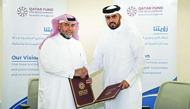 Director General of Qatar Fund for Development Khalifa bin Jassim al-Kuwari and CEO of Qatar Charity Yousif bin Ahmed al-Kuwari shake hands after signing the grant agreement.