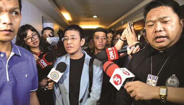 Journalist Maria Ressa (centre) is surrounded by the press as she is escorted by National Bureau Investigation (NBI) agents at its headquarters after her arrest in Manila, yesterday.