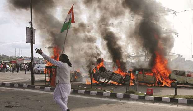 A demonstrator stands next to burning cars during a protest in Jammu yesterday.