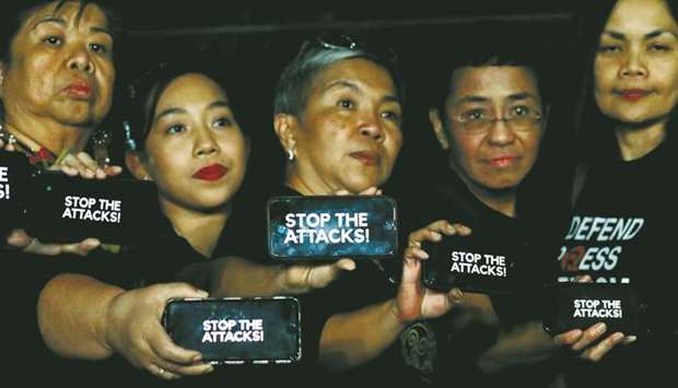 Journalists, including Rappler CEO Maria Ressa, raise their smart phones with words u201cStop The Attacks!u201d in a rally for press freedom in Quezon City, yesterday.