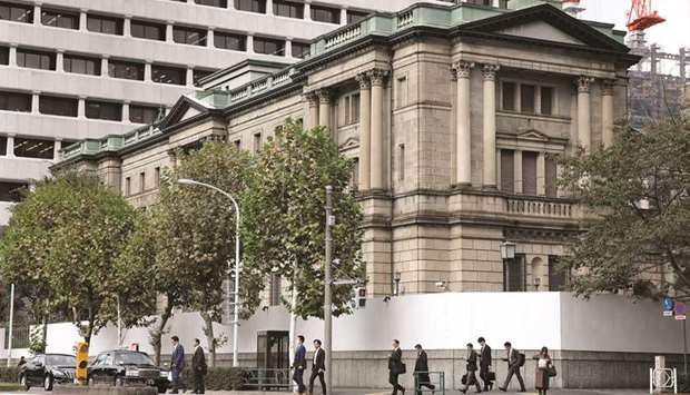 Pedestrians cross a road in front of the Bank of Japan headquarters in Tokyo. The BoJu2019s policy of pinning 10-year rates near zero means foreign demand for JGBs will strengthen, particularly as the Federal Reserve and the ECB are turning dovish, according to Nomura Securities Company.