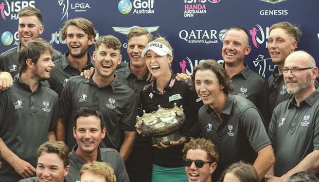 Nelly Korda (centre) of the US poses with the winneru2019s trophy and grounds staff following her Australian Open victory yesterday. (AFP)