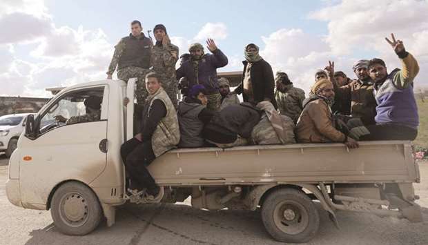 Members of Syrian Democratic Forces (SDF) gesture as they ride a truck in the village of Baghouz, Deir Al Zor province, yesterday.