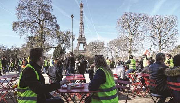 People sit at the Champ de Mars garden during a demonstration, called yesterday by the u2018yellow vestu2019 (gilets jaunes) movement near the Eiffel Tower in Paris, to mark the third month of protests.