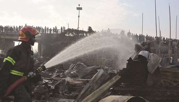 A firefighter works to extinguish fire at a slum where at least nine people were killed in Chittagong yesterday.