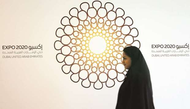 A woman walks past the logo of the Expo 2020 in Dubai (file). The grim outlook suggests the World Expo in Dubai next year wonu2019t be a game changer for its ailing real estate.