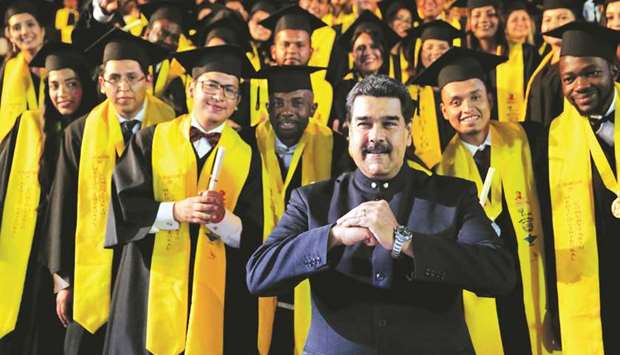 Venezuelau2019s President Nicolas Maduro gestures while posing with doctors of the 6th Graduation of Integral Community Medicine in Caracas, Venezuela.