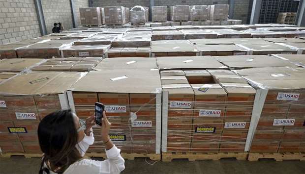 A woman photographs boxes containing humanitarian aid for Venezuela inside a warehouse at the Tienditas International Bridge in Cucuta