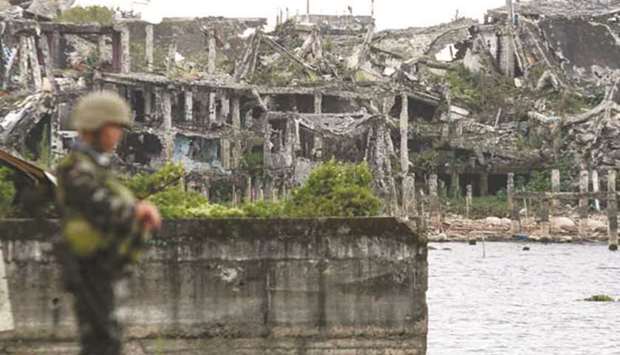 A soldier stands near ruined buildings in Marawi City.