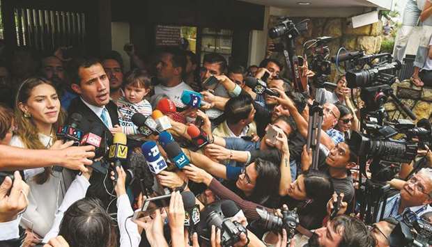 Opposition leader and self-proclaimed u201cacting presidentu201d Juan Guaido talks to the press as he holds his daughter Miranda, next to his wife Fabiana Rosales, outside his home in Santa Fe, Caracas.