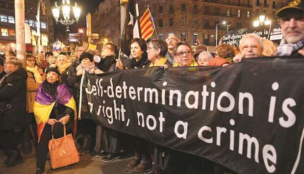 A woman wrapped in a Republican flag stands next to protesters holding a banner reading  u2018Self-determination is a right, not a crimeu2019, in Barcelona yesterday during a demonstration in support of jailed Catalan pro-independence leaders.
