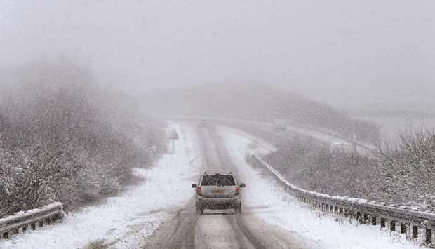 A car is driven along a slip road leading to the snow and sleet-covered A34 road a near Chievely, in Berkshire, west of London, yesterday.