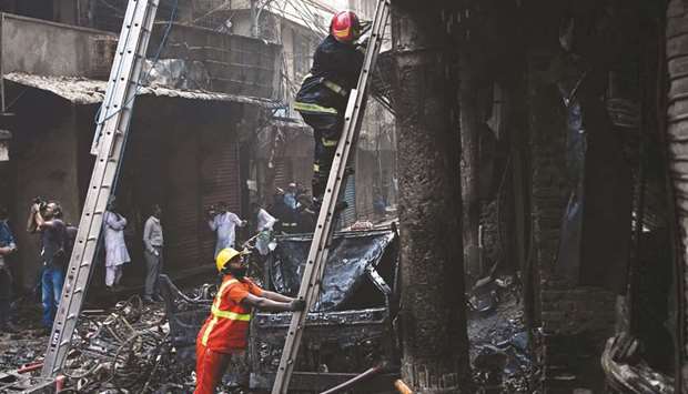 A firefighter climbs a ladder for an inspection at the disaster site in Dhaka.