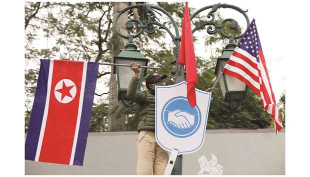 A man places North Korean and US flags outside the Opera House, ahead of the upcoming Trump-Kim summit in Hanoi.