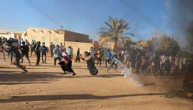 Sudanese demonstrators run from a teargas canister fired by riot policemen to disperse them as they participate in anti-government protests in Omdurman, Khartoum, Sudan on January 20, 2019