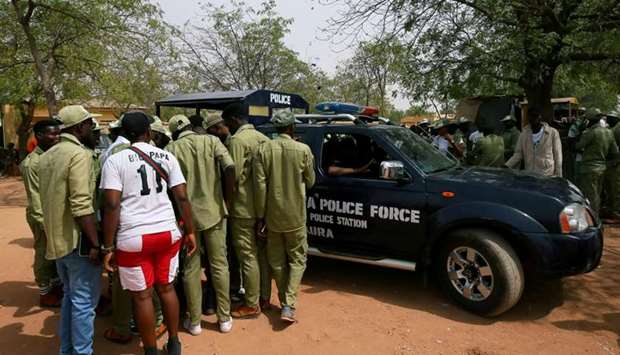 National Youth Service Corps members stand by a police car outside the Independent National Electoral Commission (INEC) office in Daura, Katsina State