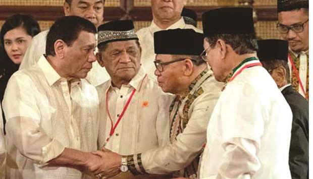 President Rodrigo Duterte shakes hands with Moro Islamic Liberation Front chairman Murad Ebrahim during the oath-taking of members of the Bangsamoro Transition Authority at the Malacanang Palace.
