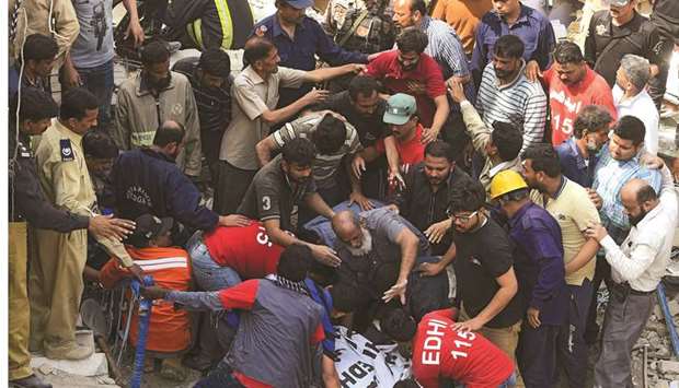 Volunteers remove the body of a victim from the rubble of the three-storey residential building in Karachi