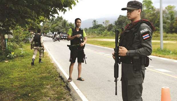 Police personnel secure the area where authorities recover the bodies of two policemen in the restive southern Thailand province of Narathiwat yesterday.