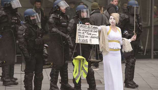 A protester dressed as Lady Justice stands near riot police officers during an anti-government demonstration in Strasbourg called by the u2018yellow vestsu2019 (gilets jaunes) movement. Her placard reads u2018Officers: The thugs are not in front, but above youu2019.