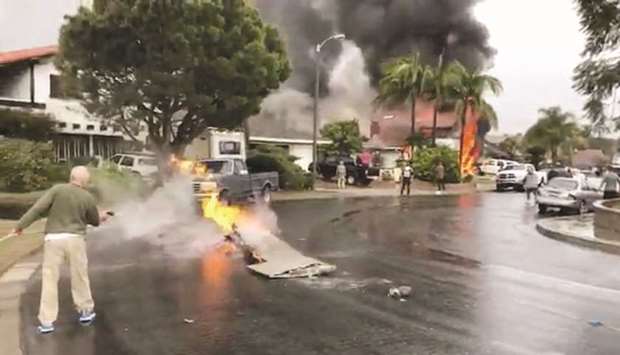 A man puts out fire on a piece of debris from a plane that crashed into a house in a residential neighbourhood in Yorba Linda, California.