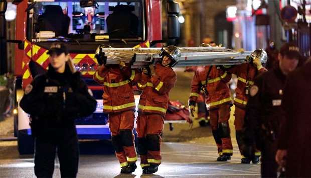 Firefighters carry a lader near a building that caught fire in the 16th arrondissement in Paris