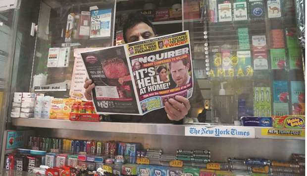 A newspaper vendor on Third Avenue in midtown New York City displays a copy of the National Enquirer at his newstand.